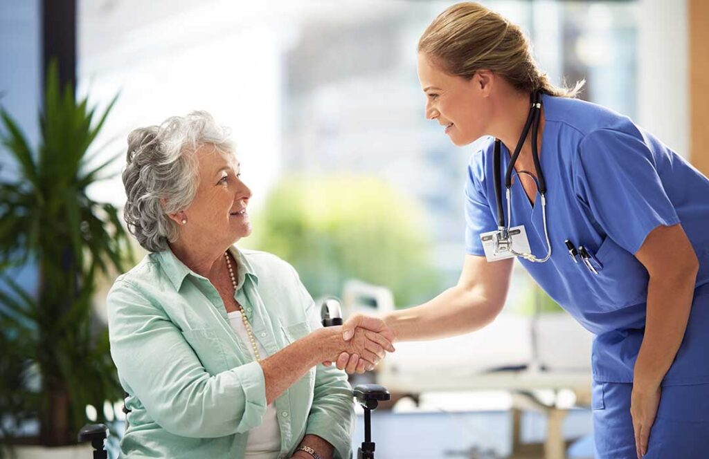 Older adult choosing clothing with a caregiver in a bright private room.