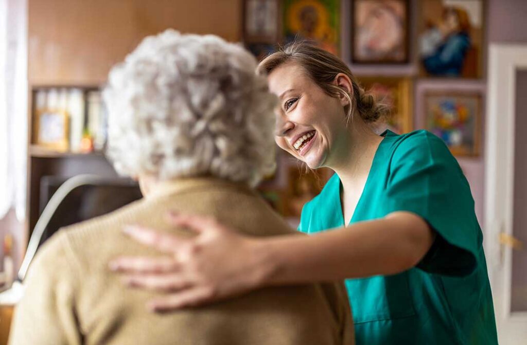 Resident writing notes during a private conversation with an assisted living staff member in a lounge.