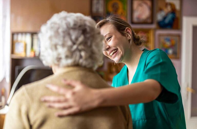 Resident writing notes during a private conversation with an assisted living staff member in a lounge.
